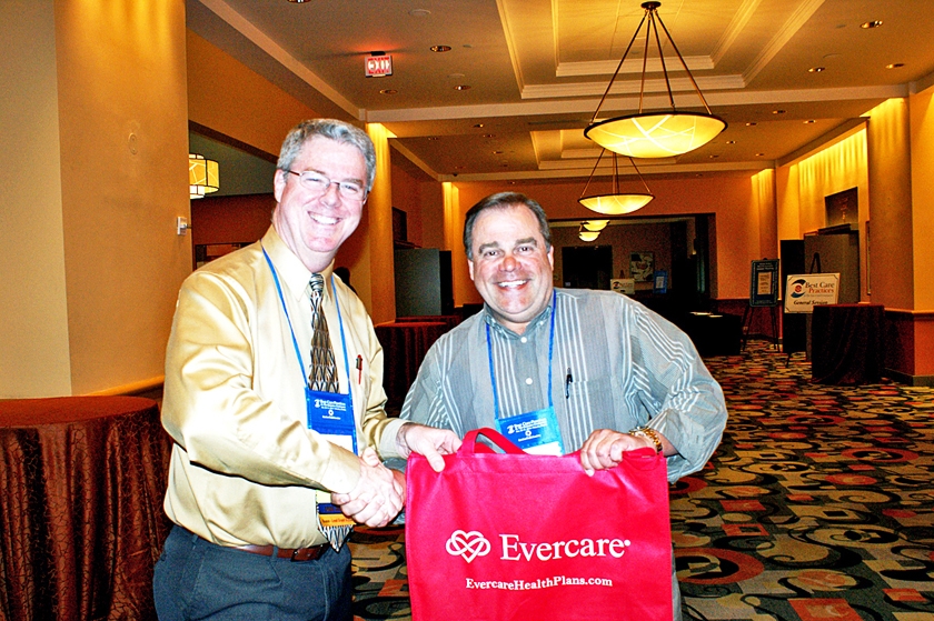 DSC03666.JPG - FMDA Director Dr. Greg James with Evercare (left) gives out one of their bags at the Welcome Reception.